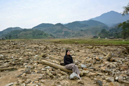 Nguyen Thi Kim sitting on a pillar of a destroyed house at the original site of Lang Nu village in Lao Cai province, after part of it was wiped away in a landslide triggered by Typhoon Yagi
