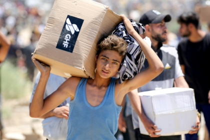 A boy carries a box of relief supplies from the Gaza Humanitarian Foundation in the central Gaza Strip - Eyad BABA (AFP)