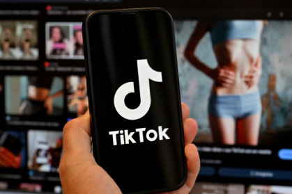 Photo d'illustration du 7 mai 2025 montrant le logo de Tik Tok sur un smartphone devant un écran affichant l'image d'une femme très mince, alors que la tendance .jpg