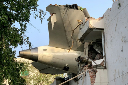The tailpiece of the crashed Air India Dreamliner juts from a building in Ahmedabad - Sam PANTHAKY (AFP)