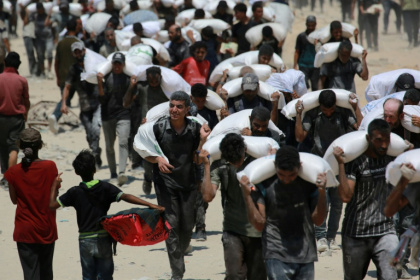 Palestinians carrying sacks of flour after trucks carrying humanitarian aid entered northern Gaza - BASHAR TALEB (AFP)