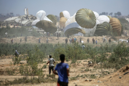 Palestinians rush to the site where parachuted aid packages in the Nuseirat area in the central Gaza Strip - Eyad BABA (AFP)