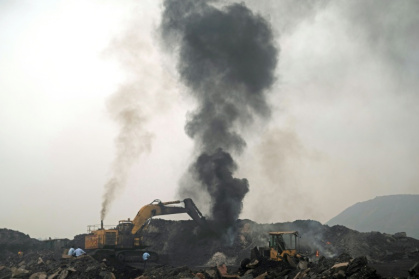 A plume of smoke rises as a worker operates a bulldozer to convey heaps of raw coal on the outskirts of Dhanbad, in India's Jharkhand state - Vishal kumar singh (AFP)