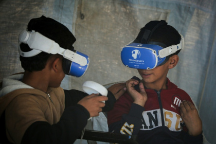 Palestinian children using goggles and a joystick experience virtual reality as part of a therapy programme - Eyad Baba (AFP)
