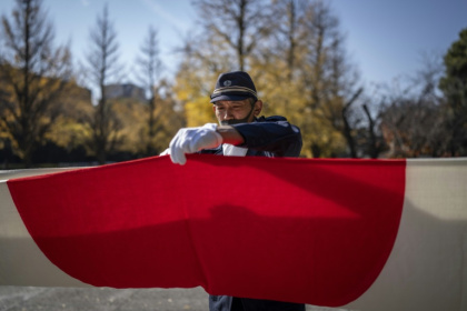 A member of the ultra-nationalist group Taikosha folds a Japanese national flag following a ceremony at Yasukuni shrine on the 84th anniversary of Japan's Pearl Harbour attack - Yuichi YAMAZAKI (AFP)