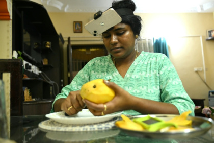 Indian housewife Nagireddy Sriramyachandra wears a smartphone on her head as she records her actions through motion capture while slicing mangoes at her home in Chennai - R.Satish BABU (AFP)