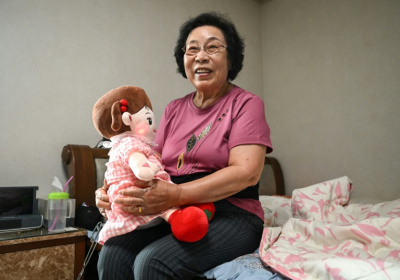 Bang Chun-ja, a South Korean elderly woman living alone, holds Hyodol, an AI-powered healthcare doll designed for elderly people, during an interview with AFP at her home in Yongin - Jung Yeon-je (AFP)